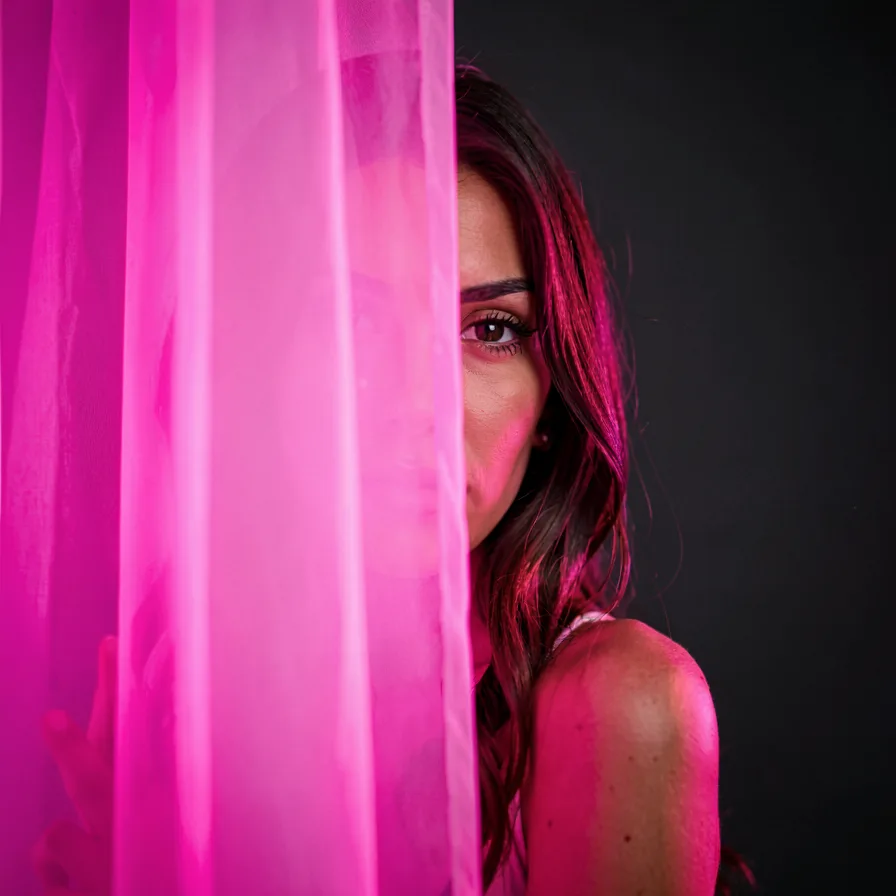 A woman peering curiously from behind a glowing curtain of light